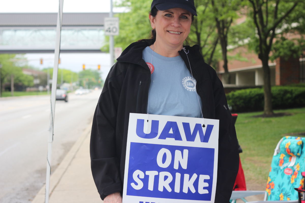 A woman holds a sign reading "UAW ON STRIKE"