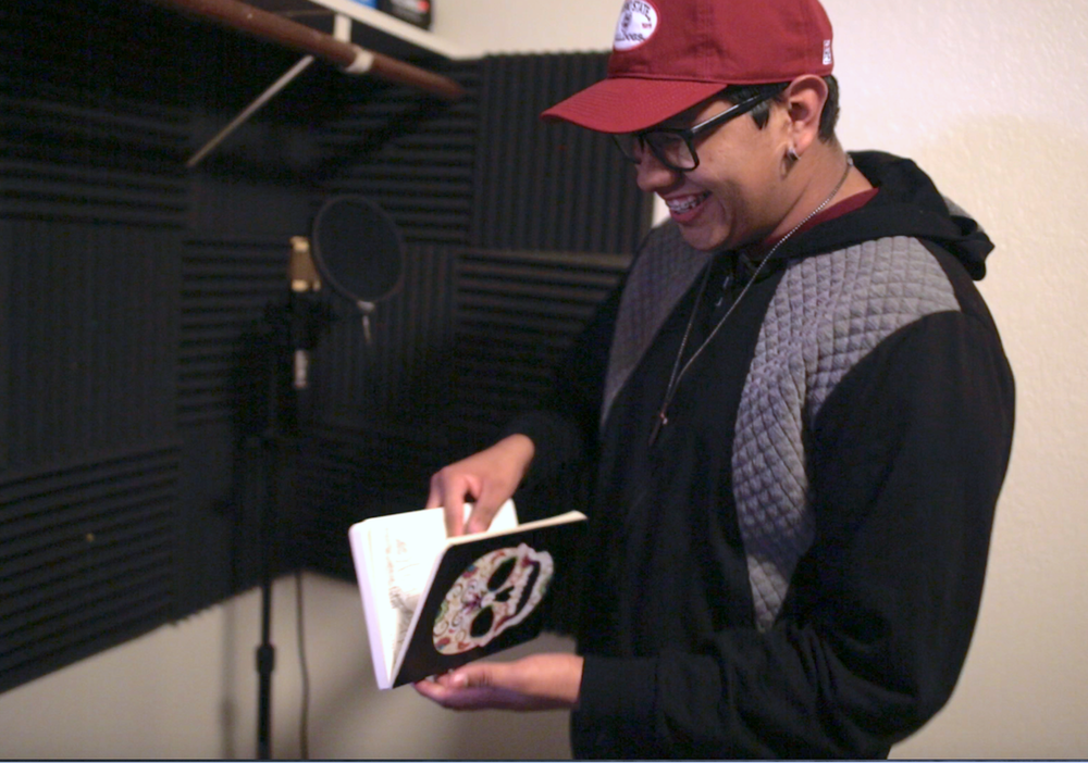 A young man smiles down at a notebook