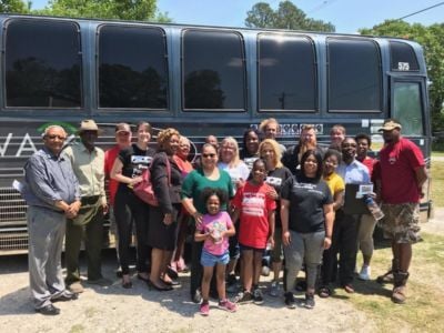 A diverse group of people stand outside of a black bus