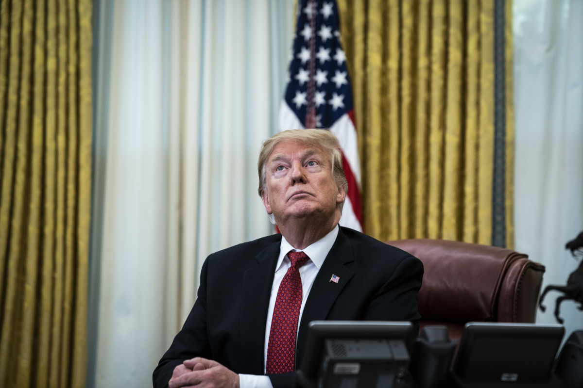 Donald Trump sits at a desk