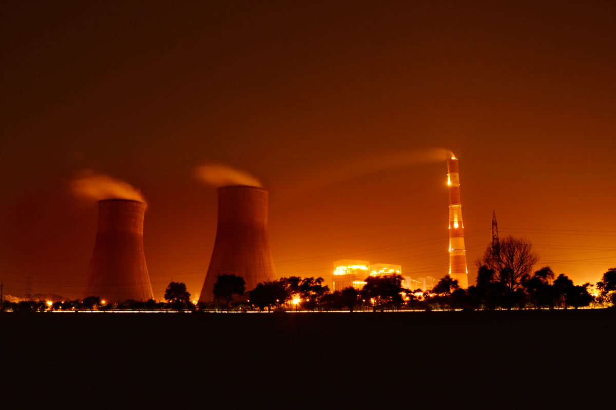Cooling towers at a nuclear power plant blow steam into an orange sky