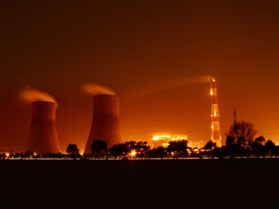 Cooling towers at a nuclear power plant blow steam into an orange sky