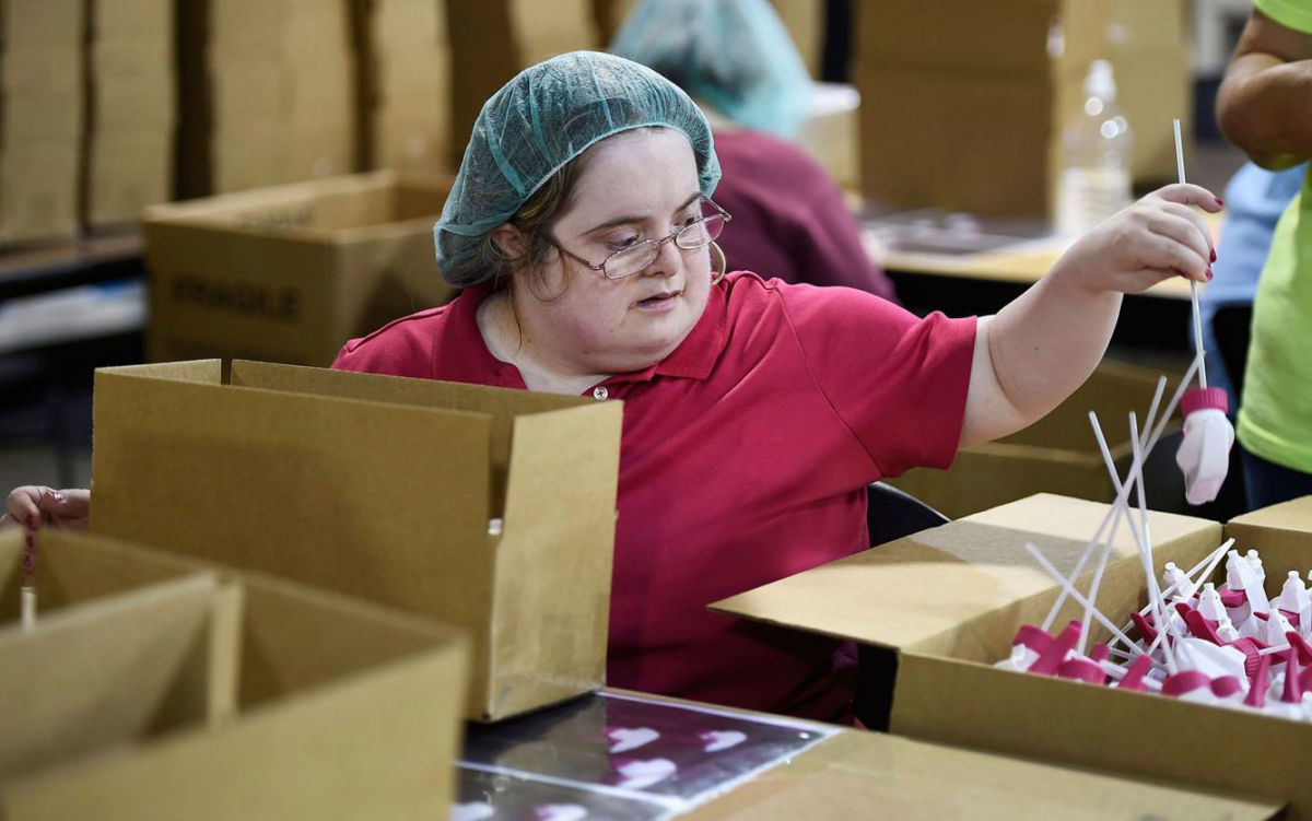 A woman repackages plastic sprayers at a sheltered workshop for adults with disabilities.