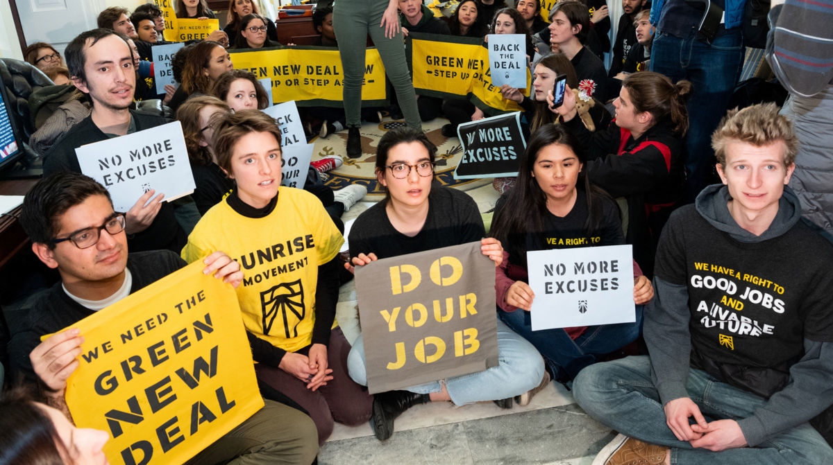 Protesters seen holding placards during the Sunrise Movement protest inside the office of US Representative Nancy Pelosi to advocate that Democrats support the Green New Deal, at the U.S. Capitol in Washington, D.C.