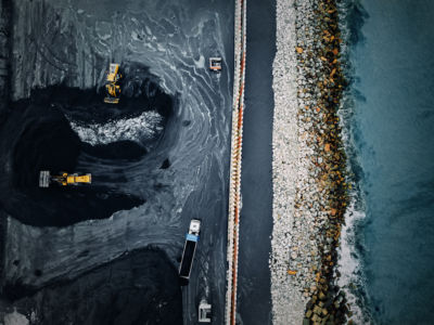 Bulldozers work with coal in a mine near a body of water