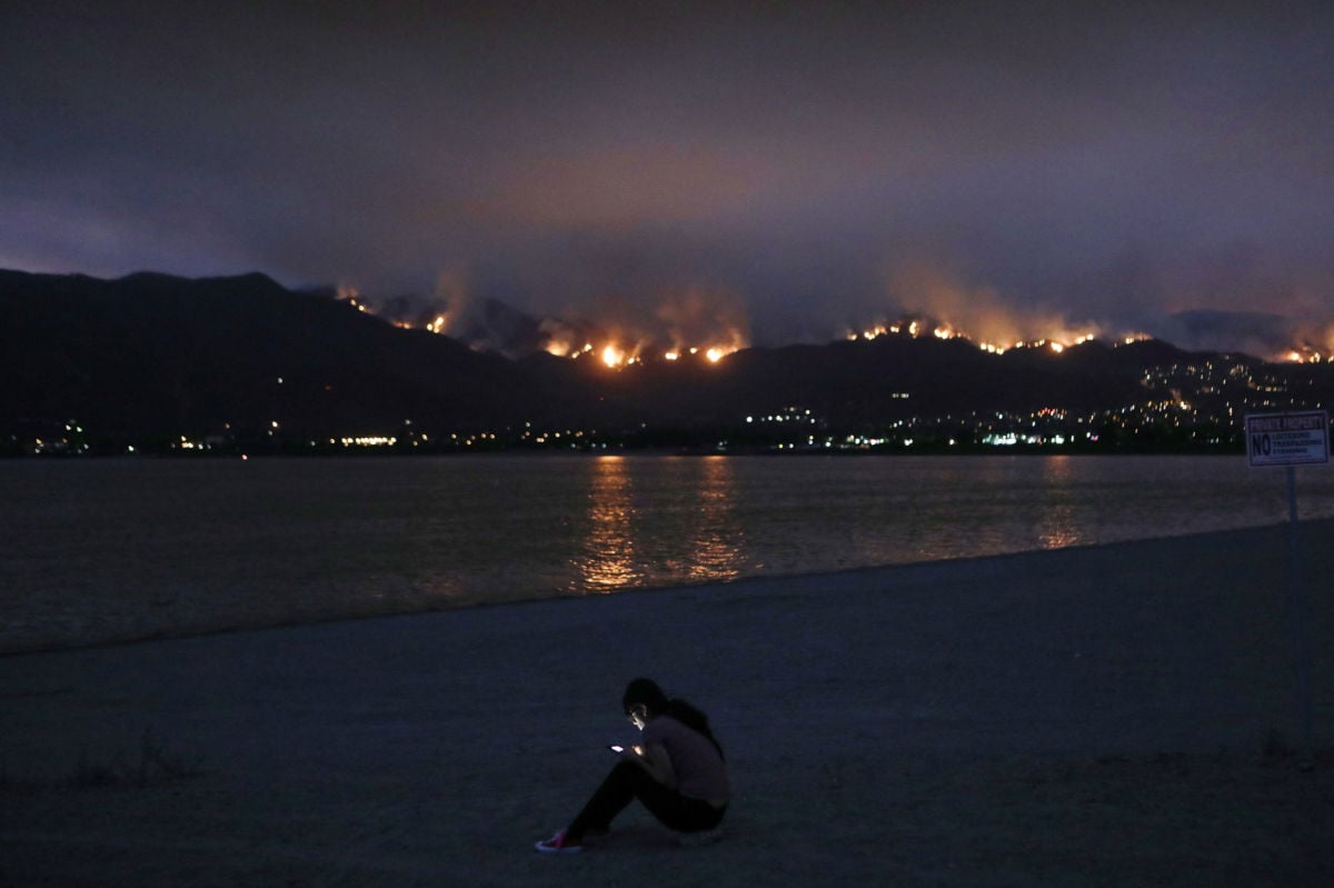 A woman checks her cell phone as the Holy Fire burns in Cleveland National Forest on August 8, 2018, in Lake Elsinore, California.