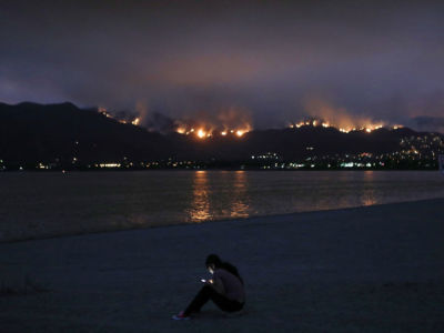 A woman checks her cell phone as the Holy Fire burns in Cleveland National Forest on August 8, 2018, in Lake Elsinore, California.