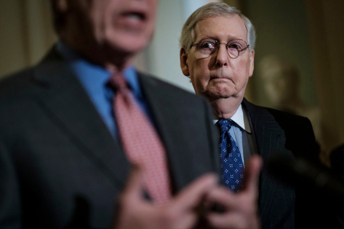 Sen. Mitch McConnell peers over someone's shoulder