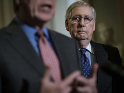 Sen. Mitch McConnell peers over someone's shoulder