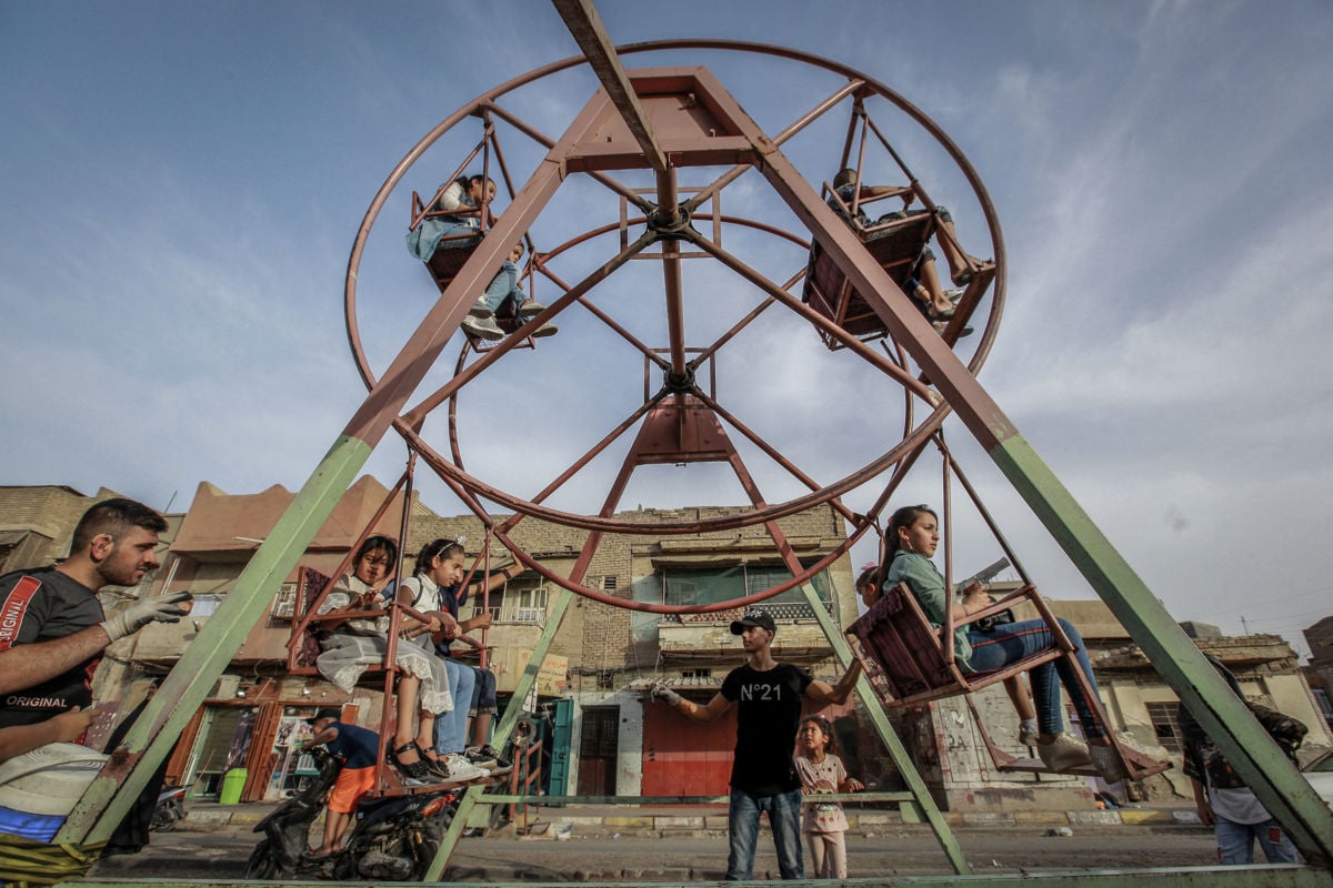 Iraqi children sit on a merry-go-round during Eid al-Fitr celebrations