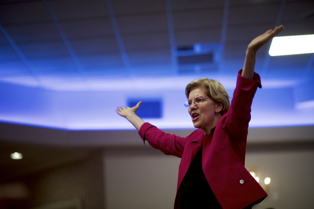 Elizabeth speaks to a crowd with her arms raised