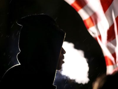Fog rises from a young man as he breathes with a U.S. flag in the background
