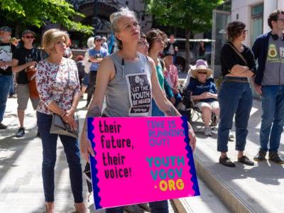 A woman holds a sign with a message of support for youth againt climate change during a rally