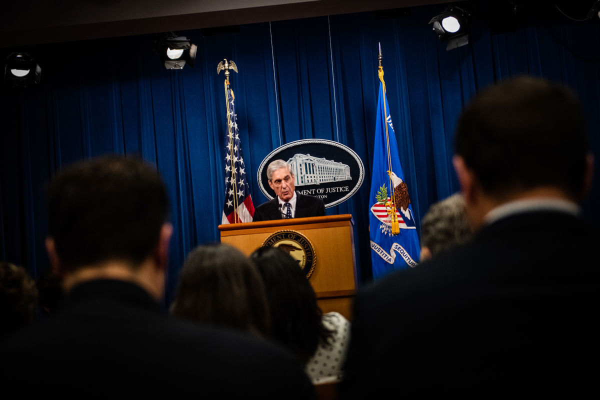 Robert Mueller stands at a podium with the emblem of the white house behind him