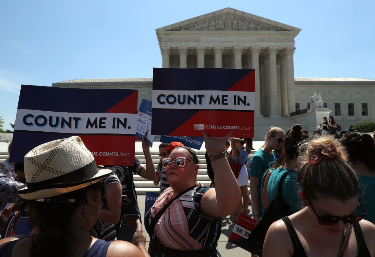 A person holds a sign reading "COUNT ME IN" during a protest outside the supreme court building