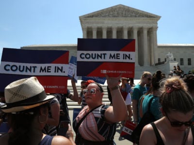 A person holds a sign reading "COUNT ME IN" during a protest outside the supreme court building