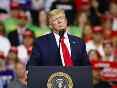 Donald Trump stands at a podium during a rally