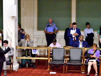 A police officer checks a mobile phone during public testimony by community members and activists on controversial social media posts by officers of the Philadelphia Police Department