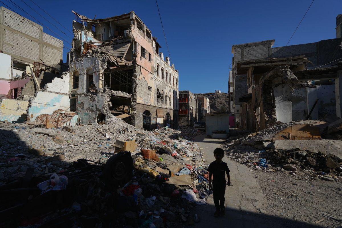 A boy walks by bombed-out buildings on November 18, 2018, in Aden, Yemen.
