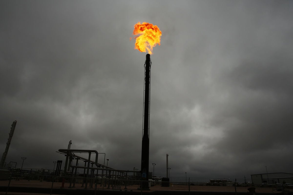 A pillar blasts a plume of fire into a cloudy sky, natural gas, fracking