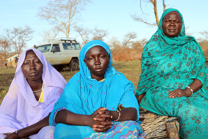 Three woman in blue, purple and turquoise chador look at the viewer