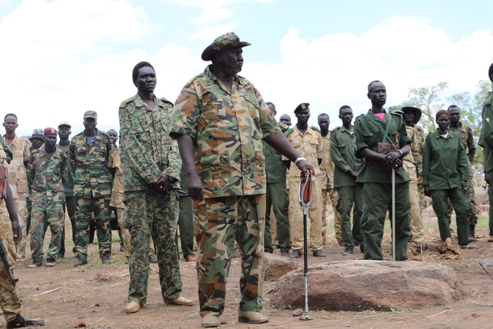 A man in an army uniform stands apart from other soldiers