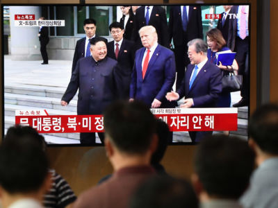 People watch a television screen showing Kim Jong Un and Donald Trump