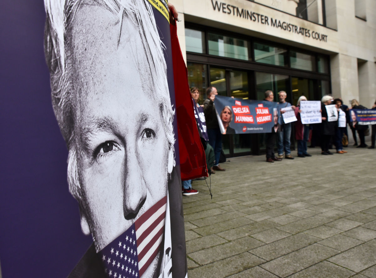 Protesters display a sign depicting Julian Assange being gagged with the U.S. Flag