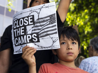 A child holds a sign during a Close The Camps protest against migrant detention centers.