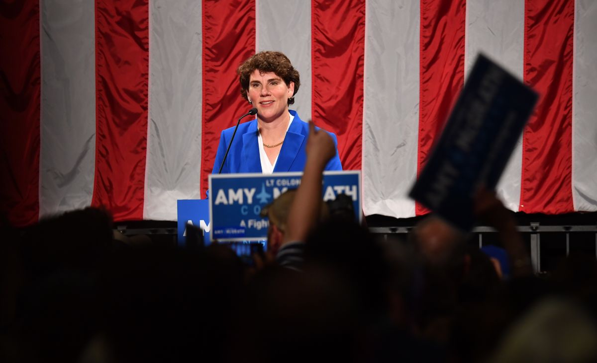 Amy McGrath stands in front of a U.S. flag and looks out at a crowd of supporters