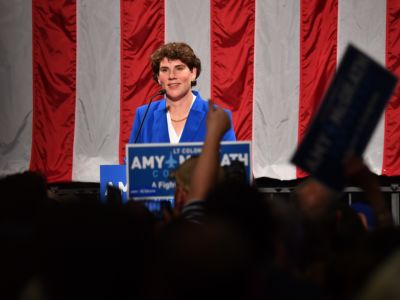 Amy McGrath stands in front of a U.S. flag and looks out at a crowd of supporters