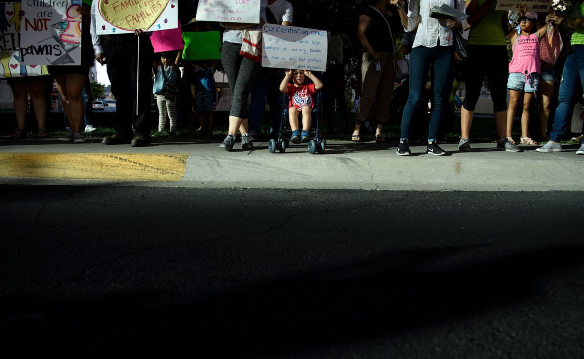 A child in a stroller holds a sign as people rally outside the El Paso County Detention Center, June 21, 2018, in El Paso, Texas.