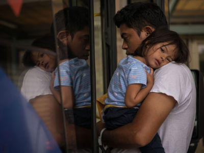 A Honduran migrant recently released from a federal immigrant jail boards a bus while carrying his 2-year-old daughter at a bus depot on June 11, 2019, in McAllen, Texas.