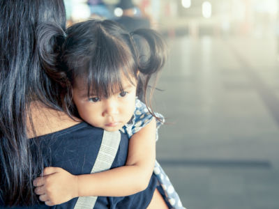 A mother hold her child while walking outside