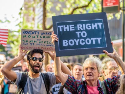 People hold signs supporting a boycott of Israel