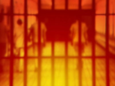 A blurred image of prisoners behind bars overlaid with red and yellow