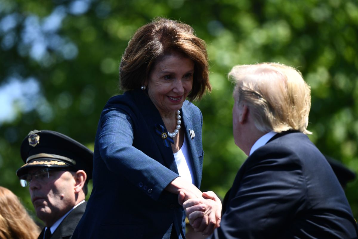 House Speaker Nacy Pelosi shakes Donald Trump's hand while grinning
