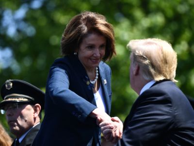 House Speaker Nacy Pelosi shakes Donald Trump's hand while grinning