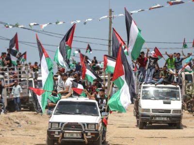 Palestinians holding Palestinian flags protest Israel's ongoing 13-year blockade, in Gaza City, Gaza, on July 22, 2019.