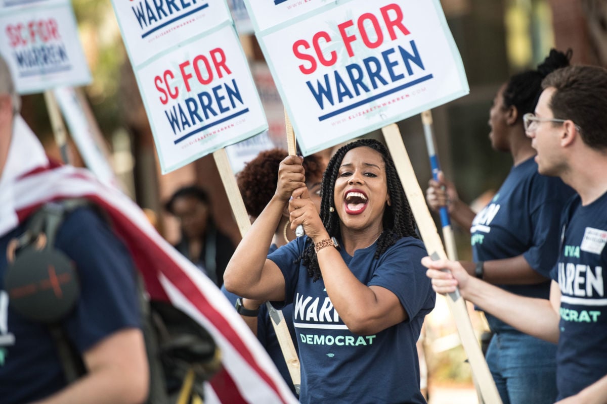 A woman cheers while holding a sign supporting Sen. Elizabeth Warren's bid for the U.S. Presidency