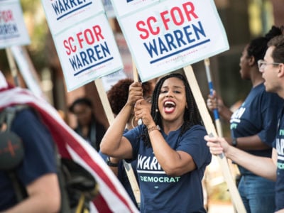 A woman cheers while holding a sign supporting Sen. Elizabeth Warren's bid for the U.S. Presidency
