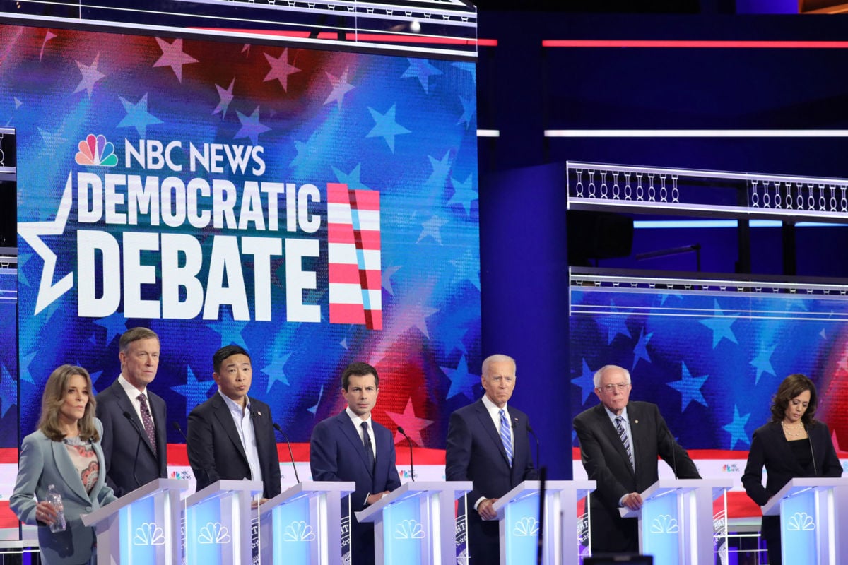 Democratic presidential candidates stand on stage in a row behind podiums