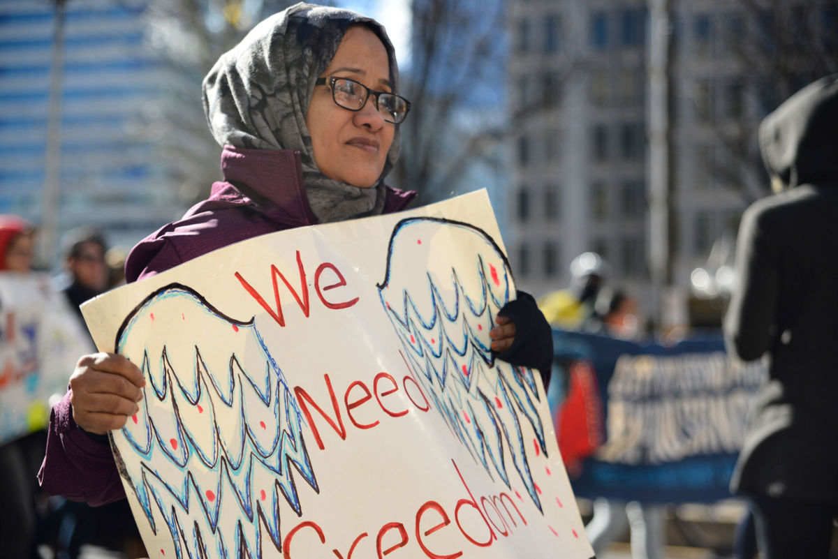A hijabi holds a sign reading "We deserve freedom" during a protest