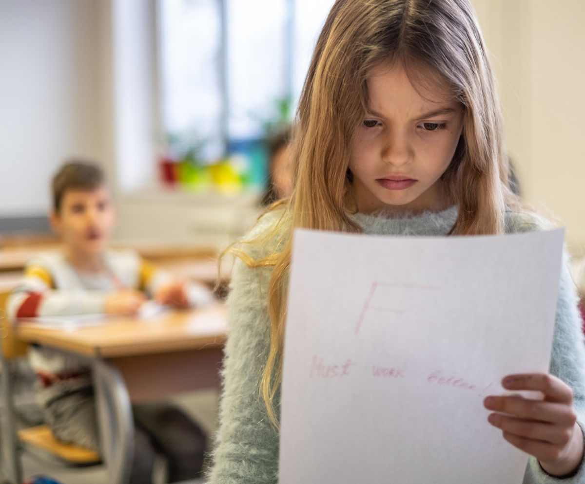 A girl looks at her report card sadly