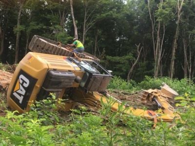 A bullzoder sits on its side in a clearing of a forest