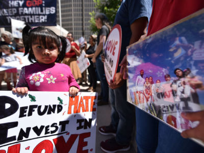 A young protester holds up a sign at a demonstration in Denver, Colorado, to demand the closure of inhumane immigrant jails, July 2, 2019.