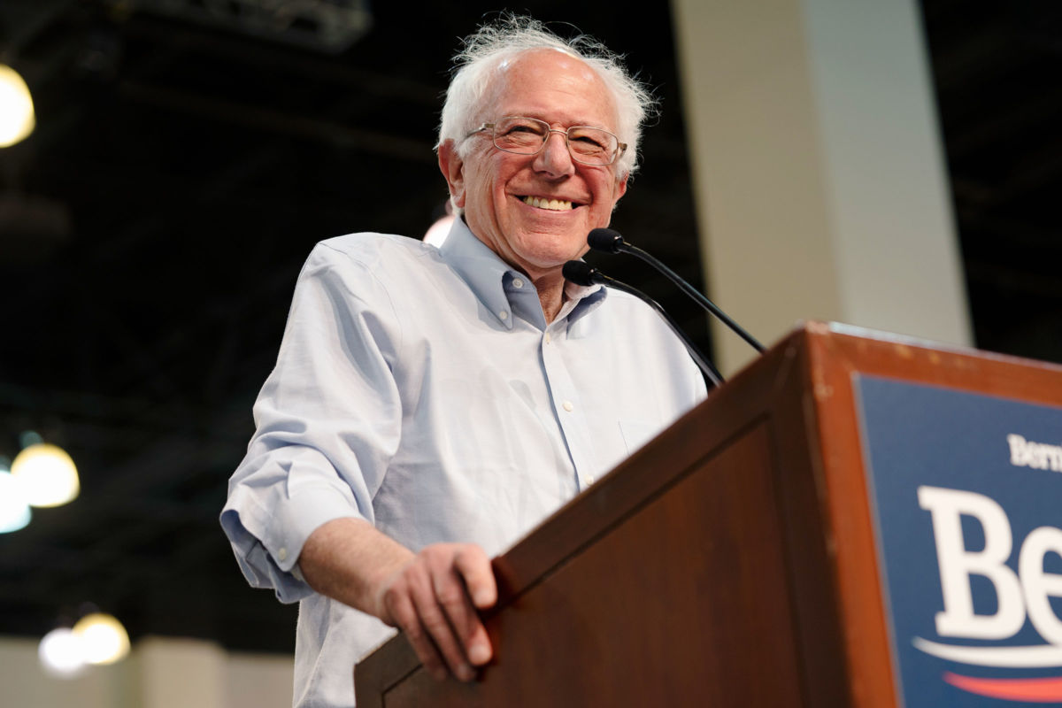 Sen. Bernie Sanders smiles while standing at a podium