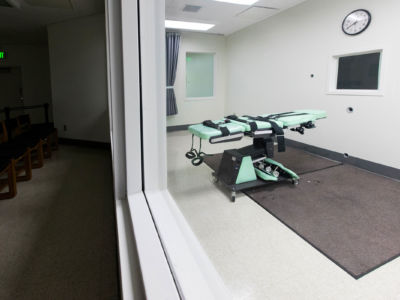 A bed used for lethal injection executions is seen from behind glass