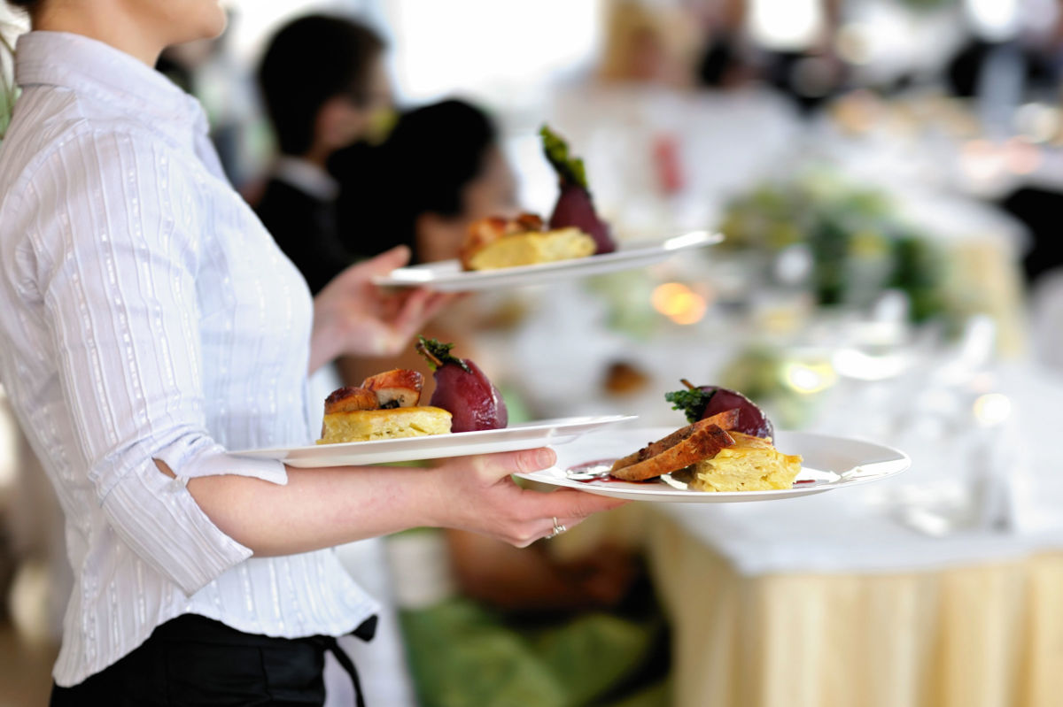 A server carries three meals in a busy restaurant