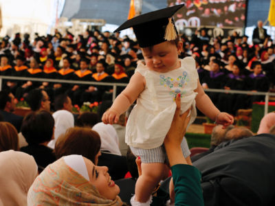 A Palestinian woman holds a baby wearing a cap during a graduation ceremony at Birzeit University in the West Bank town of Birzeit, near Ramallah, on May 20, 2016.